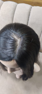 Mannequin head with black virgin hair on a beige couch